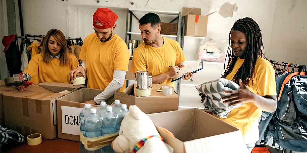 Group of volunteers wearing bright yellow shirts pack donation boxes.