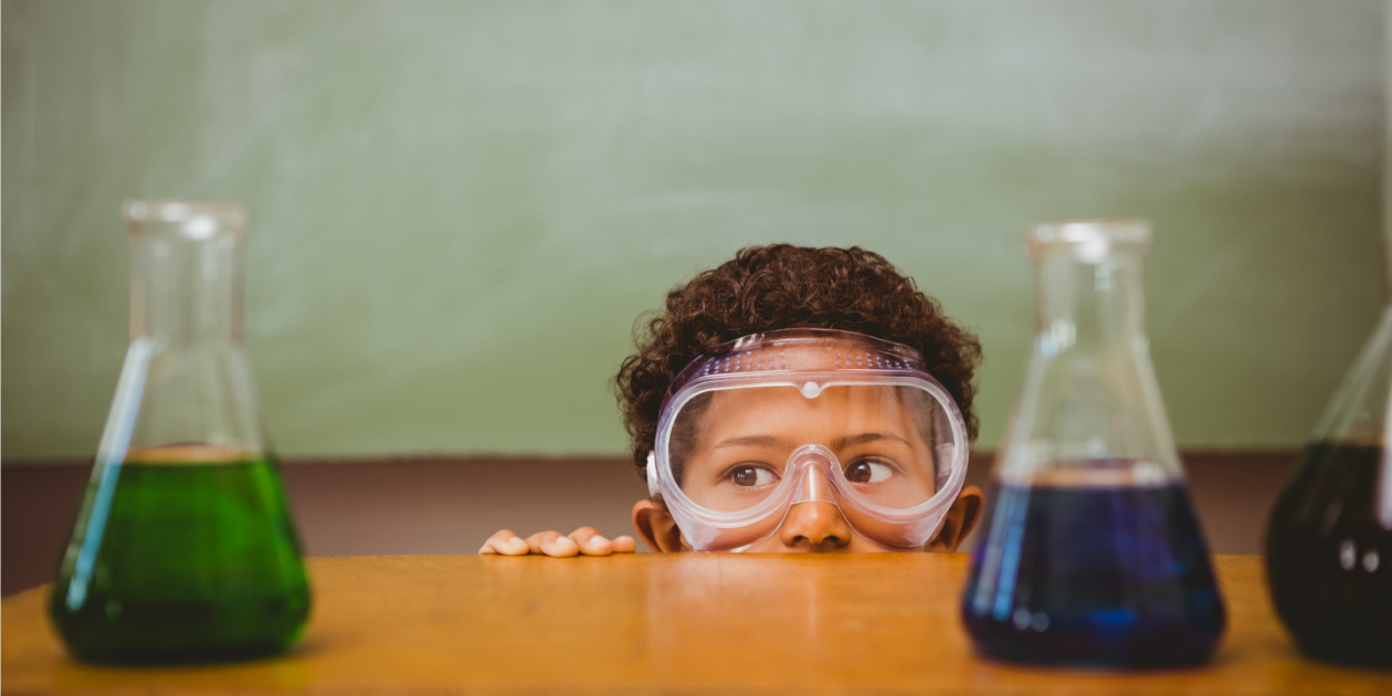 photo of young boy looking at test tubes in a classroom