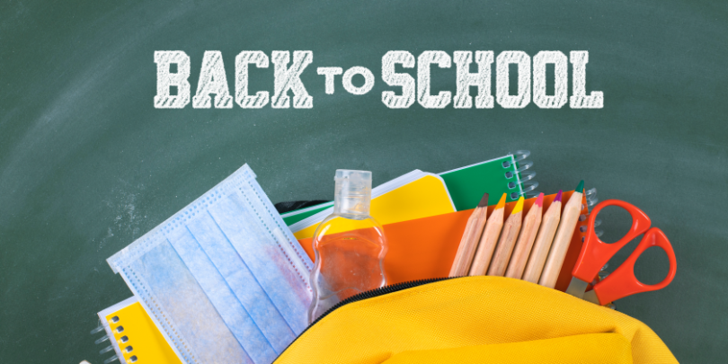 image of yellow backpack with school supplies and mask with Back to School text on chalkboard behind