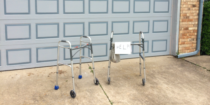 photo of two walkers in front of a garage door, with a sign taped on one reading Help