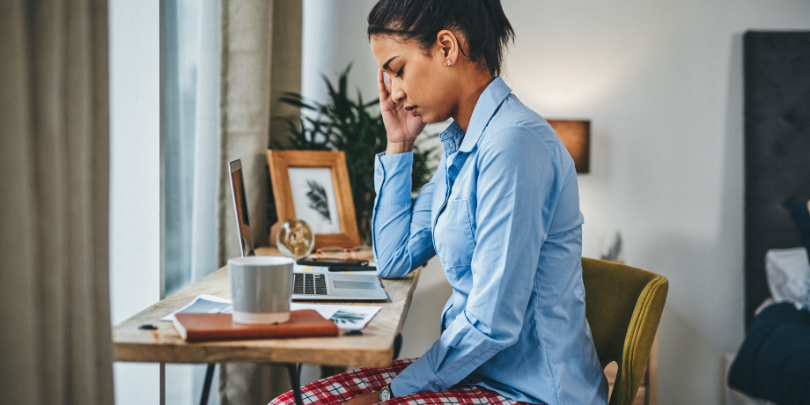 photo of woman sitting at home desk with pajama pants and dress shirt