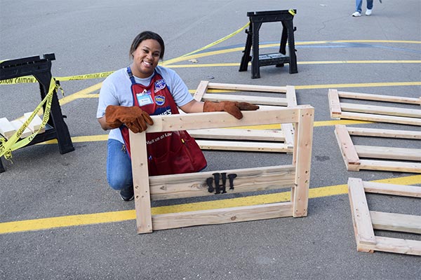 volunteer holding wooden bed headboard with sleep in heavenly peace logo