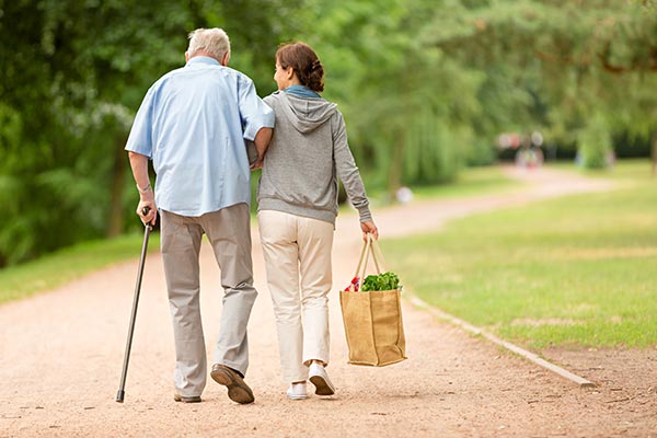 volunteer holding groceries walking with an older man