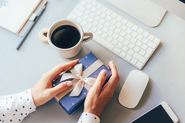 desk with keyboard mouse and a gift in the hands of a person