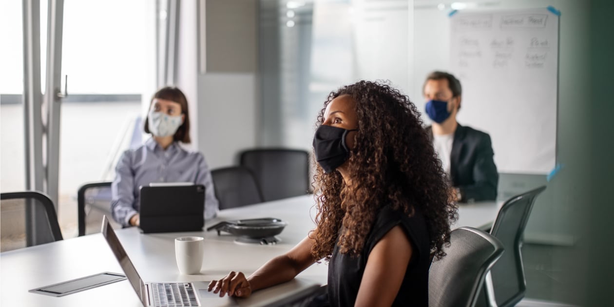 photo of three coworkers socially distanced in a conference room wearing masks