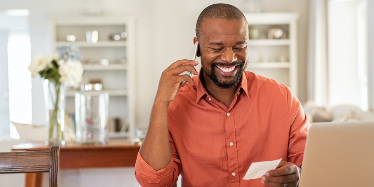 Happy man reading invoice and talking on phone