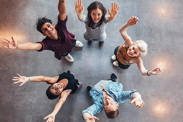 youth teens standing in circle with hands uplifted and smiling