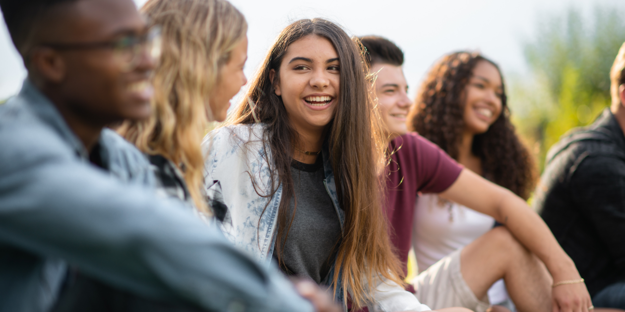 photo of teens sitting in the sun talking and smiling together