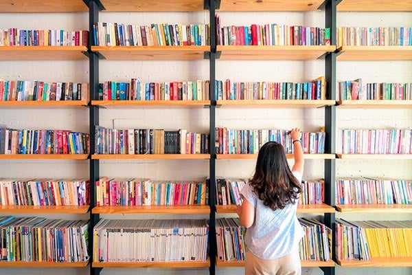 student standing in front of book shelf