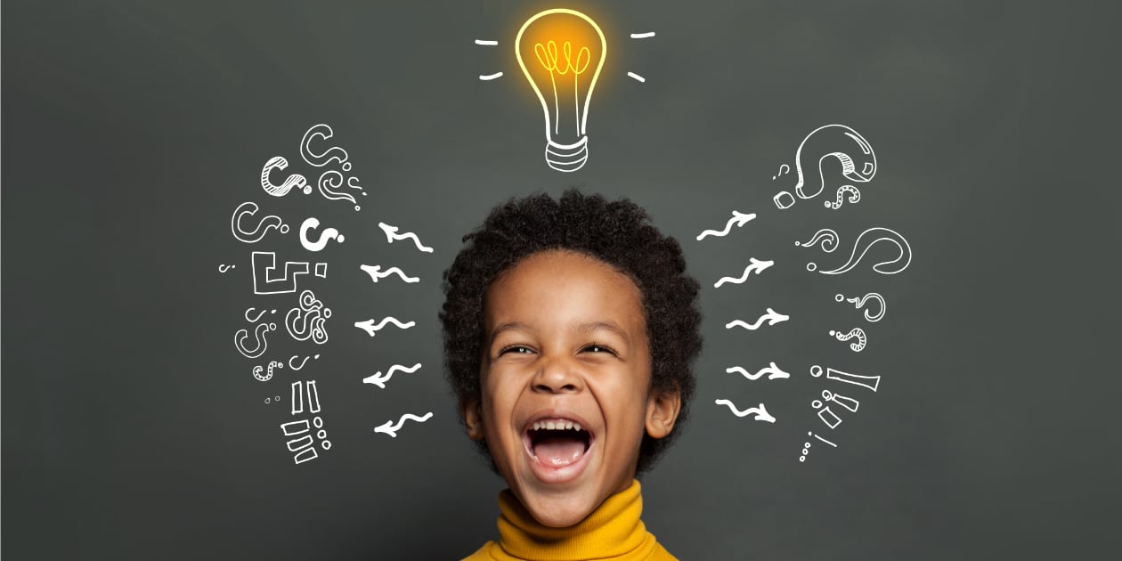 young boy wearing yellow turtleneck with lightbulb above his head and question marks and exclamation point