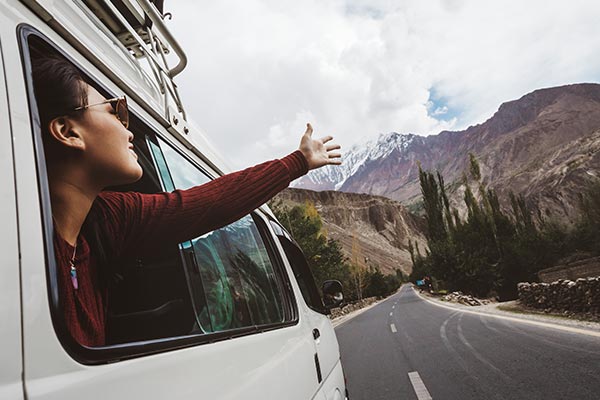 road tip van with girl holding arms out window and smiling