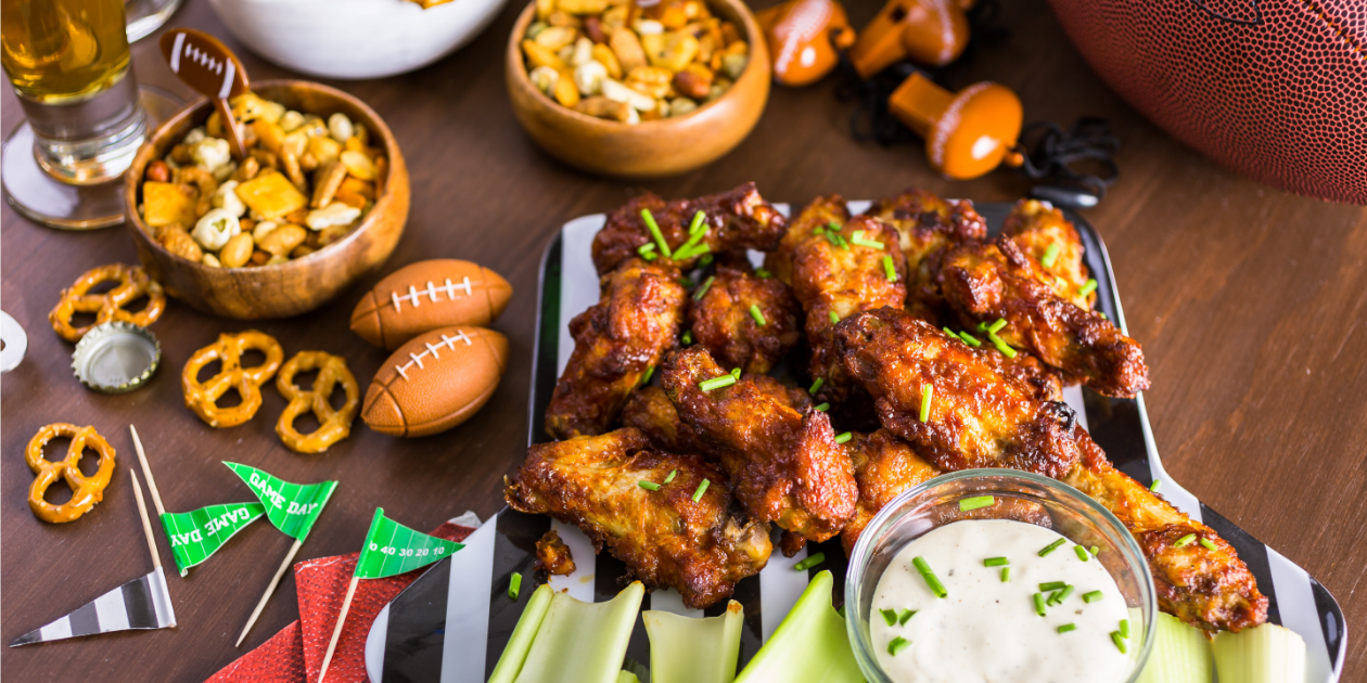 photo of chicken wings, ranch, celery and other football appetizers on a table