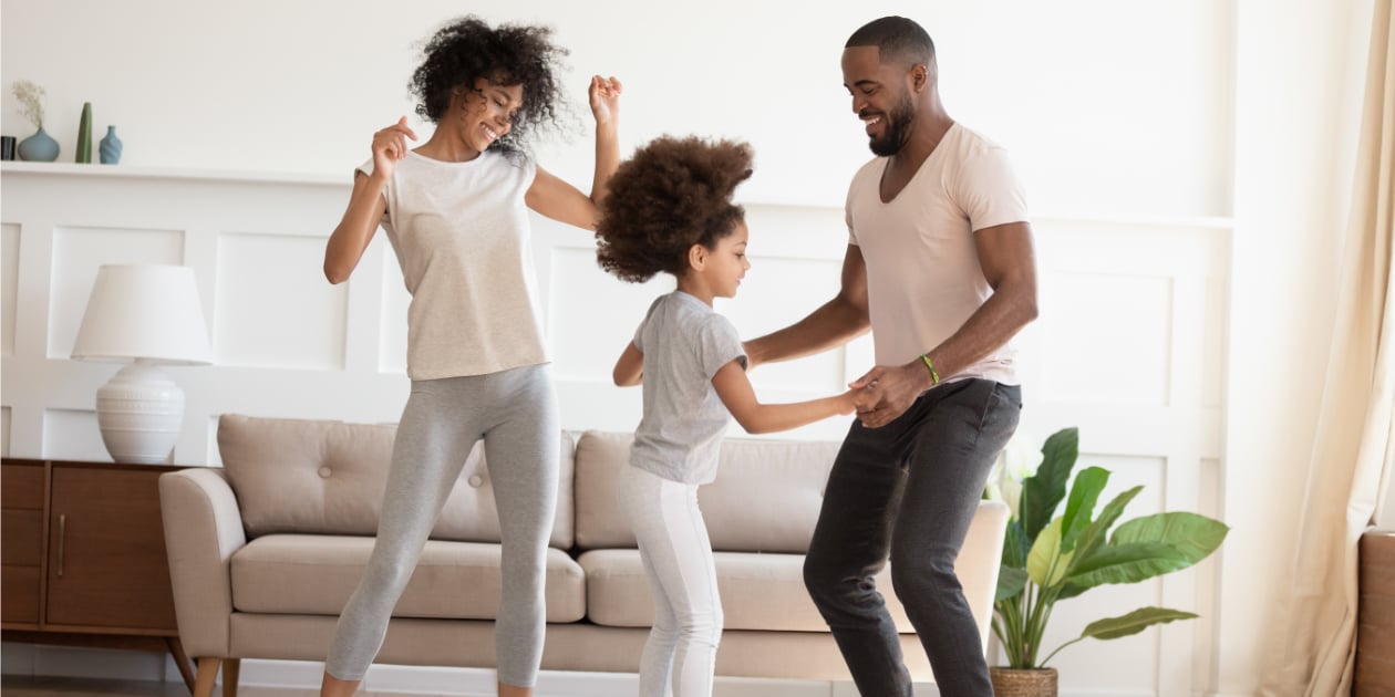 photo of parents and kid dancing in their living room