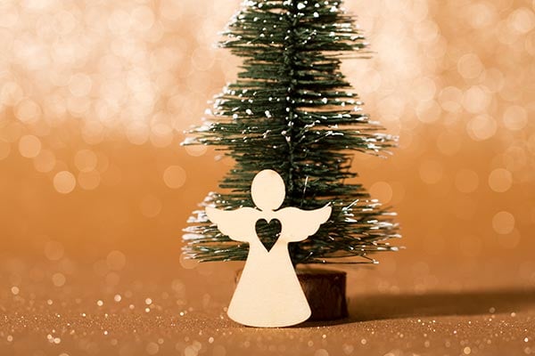 angel shaped cut out in front of small christmas tree