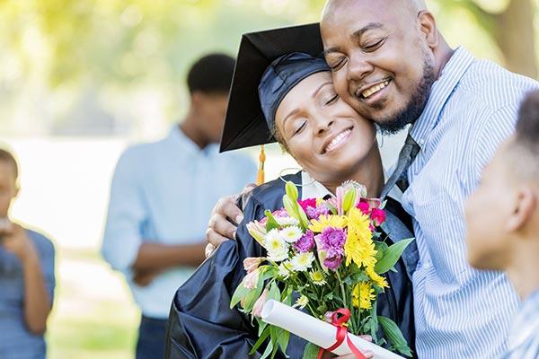 dad giving gift hugging graduate