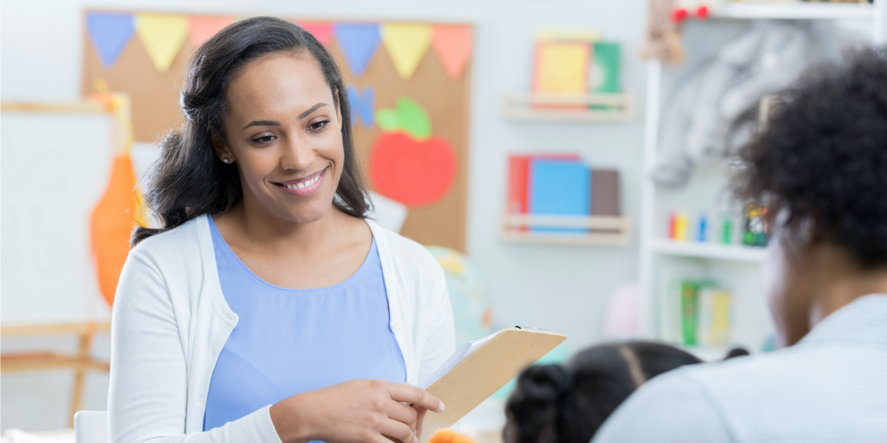 photo of a smiling teacher sitting at a meeting in the classroom