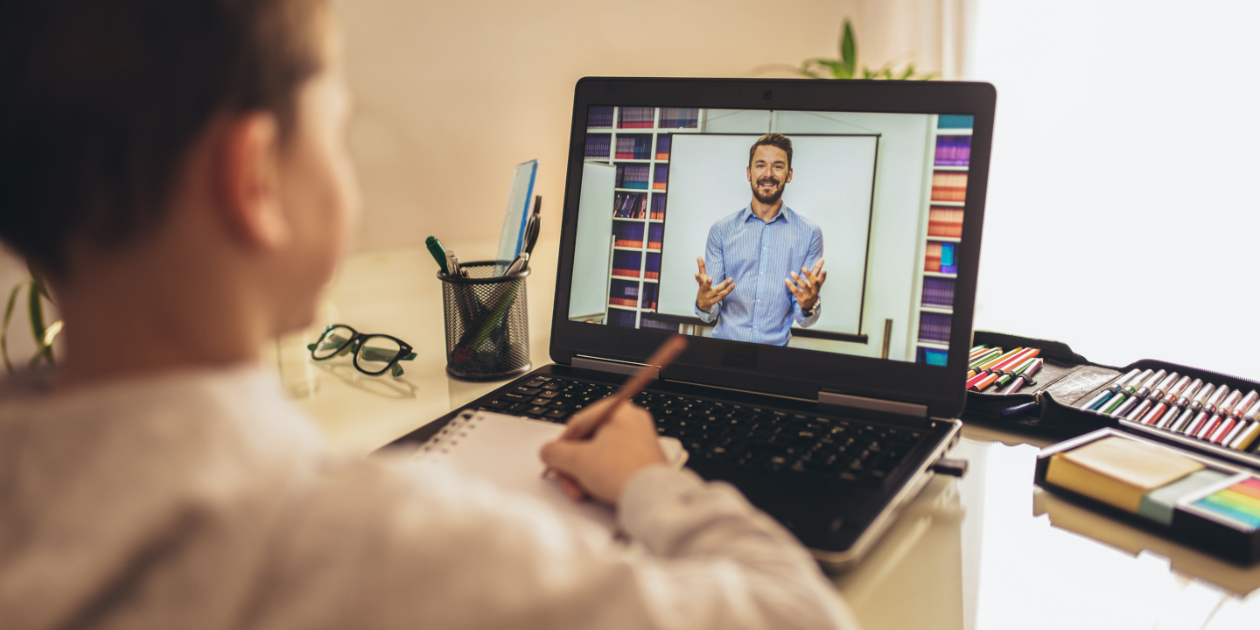 photo of boy looking at a laptop with teacher on video call