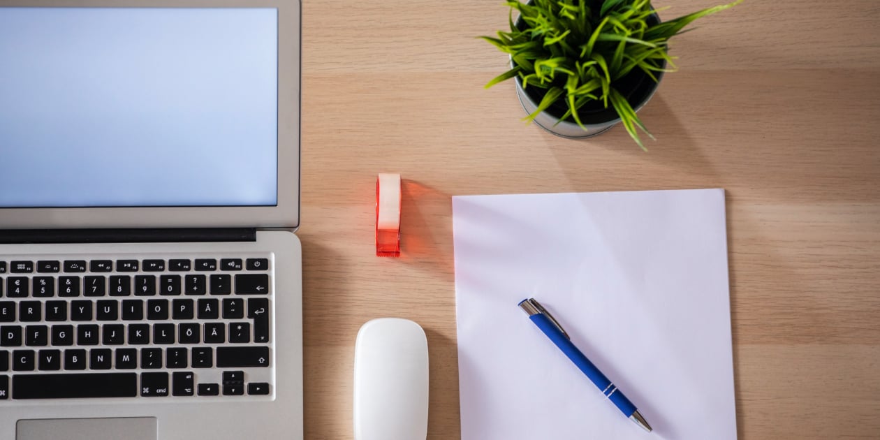 photo of clean workspace with laptop next to blank piece of paper